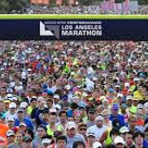 A large crowd of runners is gathered at the starting line of the Los Angeles Marathon, ready to begin the race.