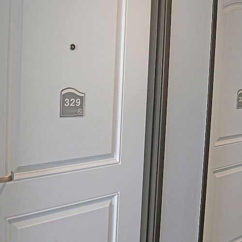 The image shows two white doors in a hallway, with door numbers 329 and 327. Both doors have electronic lock handles installed.